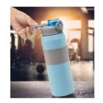 Mano sosteniendo botella turquesa en gimnasio con fondo desenfocado