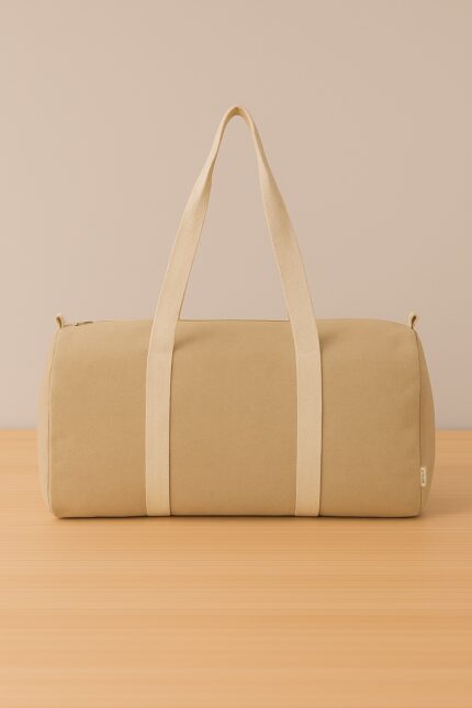 Bolso de lona beige con manijas del mismo color sobre fondo beige y superficie de madera clara.