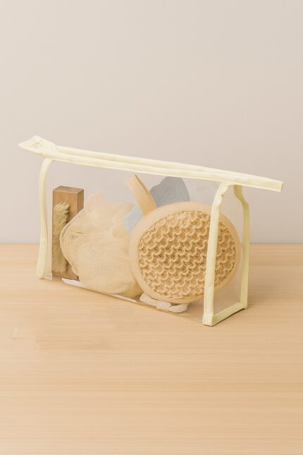 Set de spa con accesorios naturales dentro de neceser transparente beige, sobre superficie de madera clara y fondo neutro, producto de regalo corporativo MQM.